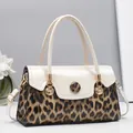 Détail du sac à main imprimé léopard avec cuir verni crème et pendentif coquillage doré - Blanc Cassé