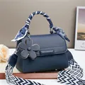 Détail d'un sac à main bleu marine en cuir grainé avec pendentif floral et bandoulière chic - Bleu