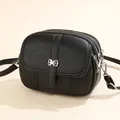Classic black crossbody round bag in lychee texture with silver bow metal clasp detail - Black