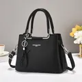 Minimalist black pebbled leather tote bag with silver hardware and star charm detail - Black