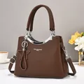 Detalle de bolso tote de cuero marrón con colgante de estrella y asas metálicas plateadas - café