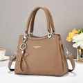 Close-up of brown litchi pattern leather tote with star charm and metallic hooks - Khaki