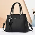 Minimalist black faux leather handbag with top handles and adjustable shoulder strap - Black