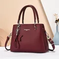 Wine red pebble leather handbag with adjustable strap and decorative tassel charm - Red