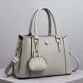Detail der cremeweißen Handtasche mit Litschi-Struktur, Goldzipper und Mini-Münzgeldbörse - Grau