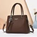 Close-up of brown litchi leather tote bag with silver hardware and star charm accessory - Coffee