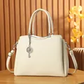 Detail of off-white lychee grain tote bag with elegant flower charm and metal hardware - Off White