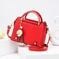 Elegant red square handbag with lychee texture and gold handle shown on a white pedestal - Red