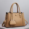 Detailansicht der khakifarbenen Ledertasche mit goldener Hardware und Mini-Anhänger - Aprikose