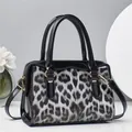 Detail of leopard print pillow bag with black patent leather trim and gold hardware - Black