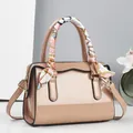Detail der glänzenden Lackledertasche mit Wellenkante und dekorativem Seidentuch-Griff - Khaki