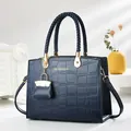 Close-up of crocodile embossed handbag with braided handles and golden metal accents - Blue