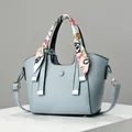 Detail van lichtblauwe emmer tas van leer met lychee-patroon en zijden sjaal op het handvat - Hemelsblauw