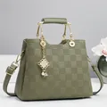Close-up of olive green checkered handbag with gold metal handle and pearl pendant detail - 26x12x20cm / Green