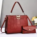 Detail view of burgundy crocodile pattern leather bag set with gold B buckle and clutch - Red