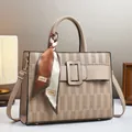 Dettaglio della borsa tote beige goffrata con fibbia quadrata e sciarpa di seta decorativa - 30cmx10cmx23cm / Cachi