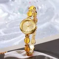 Detalle de reloj dorado con piedras de ojo de gato amarillas y números romanos en la esfera - Amarillo