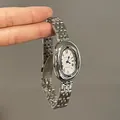 Macro detail of silver oval quartz watch with Roman numerals and steel mesh band - Silver Strap White Dial