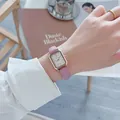 Detailopname van de lichtpaarse leren horlogeband met litchi-textuur en gouden vierkante kast - Roze