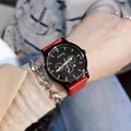 Detail of black dial quartz watch with red leather strap and small weekday sub-dial display - Red