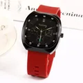 Detailed close-up of square black watch case with red silicone strap and gold accents - Red