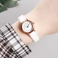 Close-up of a women's quartz watch with white leather strap and rose gold date display - White