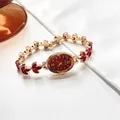 Detail of oval gold watch with ruby-red crystal leaf bracelet and wine red dial - Red