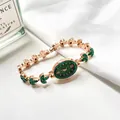 Macro detail of oval emerald green dial and rose gold gemstone bracelet watch strap - Green