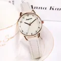 Detail of rose gold ladies quartz watch with white leather strap on a white coffee cup - White