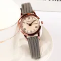 Gros plan d'une montre vintage en or rose avec bracelet en cuir gris sur une tasse blanche - Gris