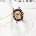 Detail van roségouden tonneau horloge met witte leren band naast een kopje koffie - Romeinse Cijfers Wit