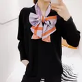 Detailed view of women's double-layer silk scarf tied in a bow with royal carriage print - Orange Edge