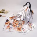 Satin silk square scarf with yellow magnolia flower prints draped on a handbag - White