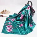 Elegant emerald silk scarf with pink magnolia floral print draped on a black handbag - Green
