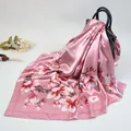 Pink floral satin square scarf with cherry blossom print draped on a handbag - Pink