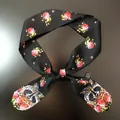 Detail of a black polyester scarf showing raccoon print, floral pattern, and the care label - Black Rose Raccoon (C141-9)