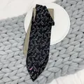 Close-up of double-sided silk twilly scarf featuring minimalist bird print and yellow patterns - Black