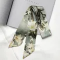 Detail of silk twilly scarf with magnolia patterns over a stylish magazine and white fabric - 95cm / Morandi Green Magnolia Style (C145-15)