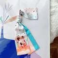 Detail view of Aries zodiac silk ribbon scarf featuring soft pastel floral illustrations - Aries