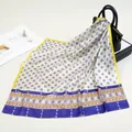 Detailed shot of a silky satin neck scarf with blue geometric stars on a leather handbag - Yellow