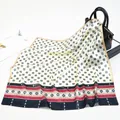 Detail of silk scarf featuring black geometric patterns and colorful borders on handbag - Khaki