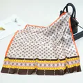 Detail of silk satin scarf with geometric pattern and ethnic border draped over a bag - Orange
