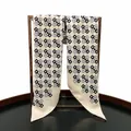 Close-up of geometric pattern on 90cm twill silk scarf displayed on a bronze stand - Beige