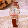 Gros plan d'une montre or rose avec nœud scintillant et bracelet en cuir marron - Café