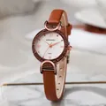 Elegant rose gold women's watch with rhinestone bezel and brown leather strap on marble - Brown