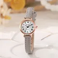 Detalle de reloj de cuarzo con números romanos, caja de oro rosa y correa de cuero gris - Gris