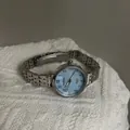 Detailed close-up of BARSH silver metal strap watch with light blue dial on white knit - Light Blue