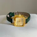 Macro shot of square gold quartz watch with green leather strap and retro dial details - Green