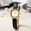 Detailed close-up of a small oval gold watch with black leather strap on a pearl base - Black Band Gold Case White Dial