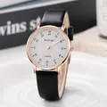 Minimalist quartz watch with rose gold case and black leather strap on a white stand - Black Strap White Dial